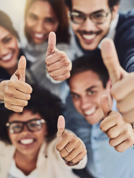 Thumbs up from a happy business team excited about the success they achieve together at work. Overhead view diverse group of corporate people excited by success and give approval to winning. - Foto, imagen