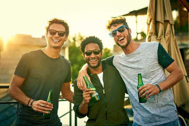 Cold ones with the crew. a group of young friends hanging out and having drinks together outdoors - Foto, imagen