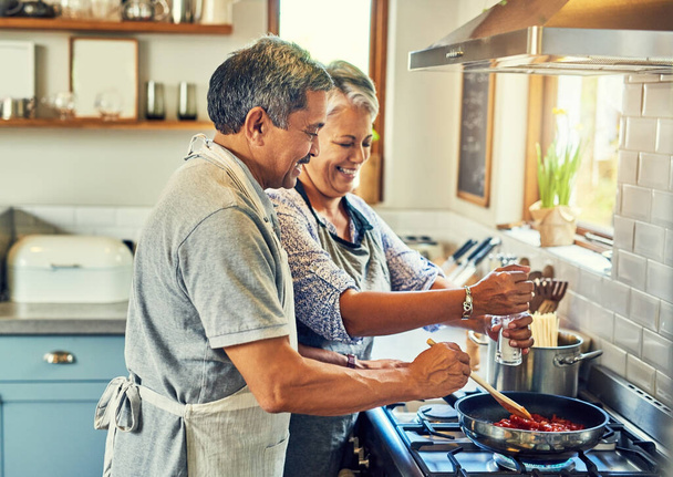 Seasoning turns good food into great food. a happy mature couple cooking a meal together at home - Photo, image