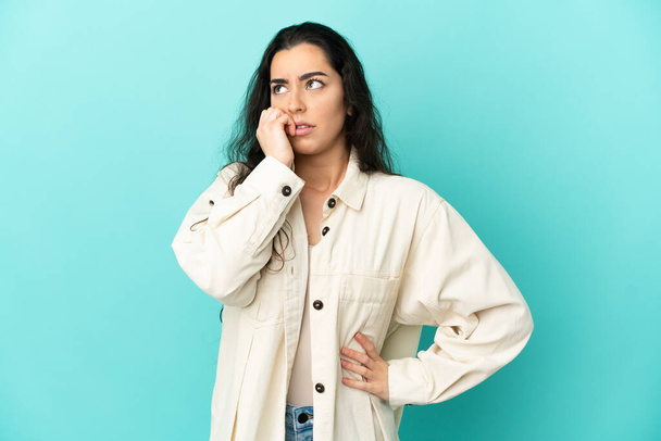 Young caucasian woman isolated on blue background is a little bit nervous - Photo, Image