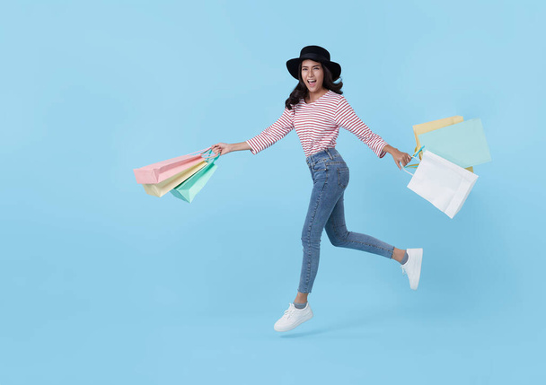 Jumping happy teen asian woman enjoying shopping, she is carrying shopping bags to get the latest offers at the shopping center. - 写真・画像