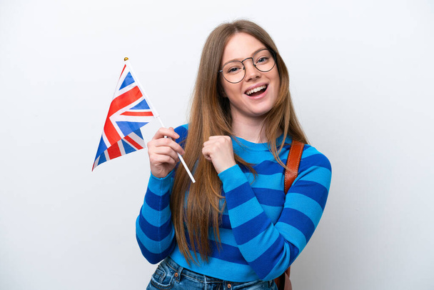 Giovane donna caucasica con una bandiera del Regno Unito isolata su sfondo bianco che celebra una vittoria - Foto, immagini