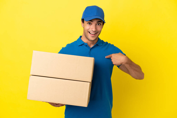 Delivery man over isolated yellow wall with surprise facial expression - Photo, image
