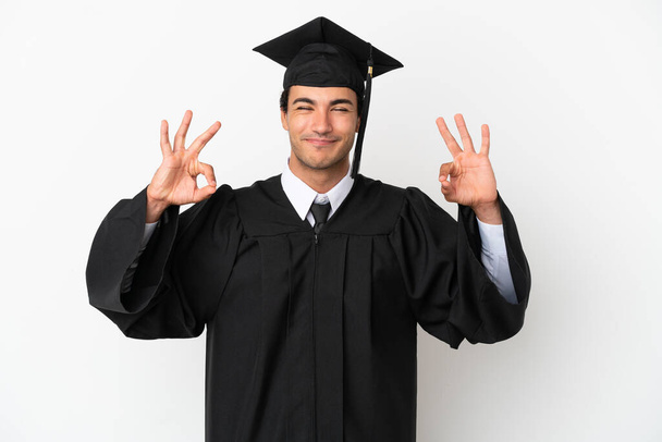 Молодой выпускник университета с изолированным белым фоном в позе дзен - Фото, изображение