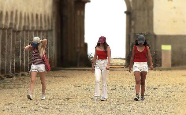 Three young tourists in white and red visiting a monastery - Foto, Imagen