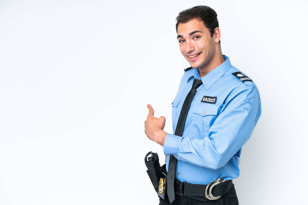 Young police caucasian man isolated on white background pointing back - Foto, Bild