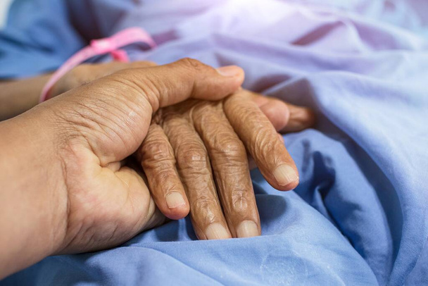 Close-up of child holding mother's hand while sick, son's hand touching elderly woman in hospital - Photo, Image