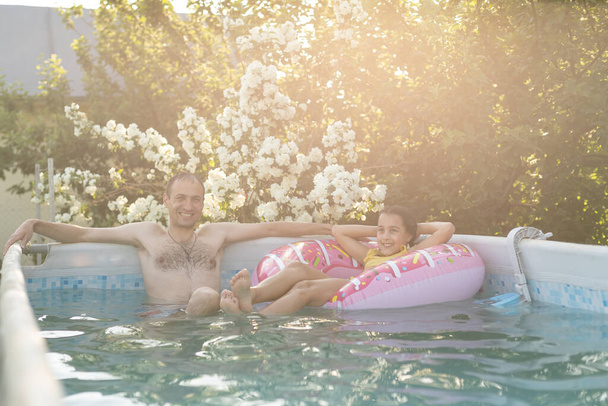 Petite fille et papa heureux s'amusent ensemble dans la piscine extérieure - Photo, image