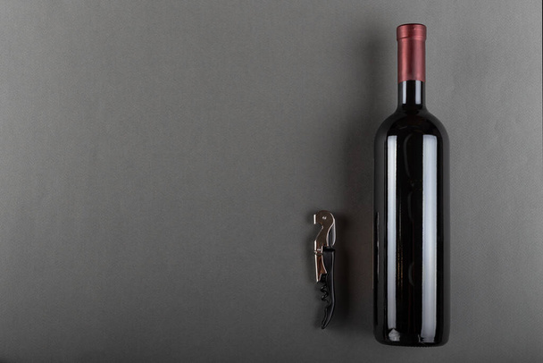 Corked bottle of red wine and corkscrew on a gray background. Alcoholic drink. Winemaking concept. Space for text. Top view. - Foto, Bild