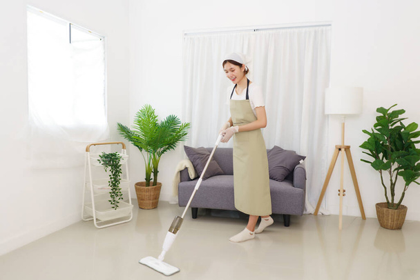 Lifestyle in woonkamer concept, Jonge Aziatische vrouw schoonmaken van de vloer met stofzuiger. - Foto, afbeelding