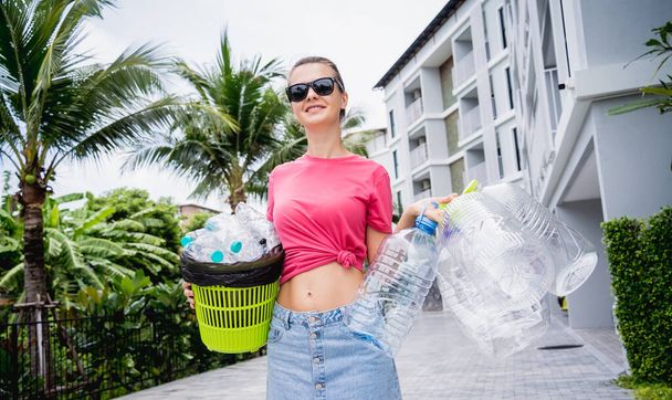 Young beautiful girl takes out the sorted garbage from the house. - Foto, Imagen