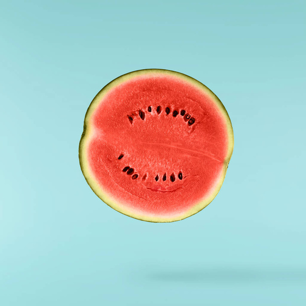 Fresh raw watermelon falling in the air isolated on blue background. Food levitation or zero gravity conception. igh resolution image. - Zdjęcie, obraz