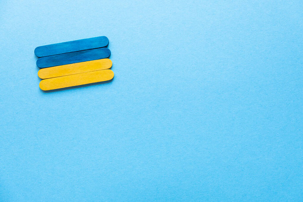 Blue and yellow wooden sticks. Flag of Ukraine on a blue background, free space - 写真・画像