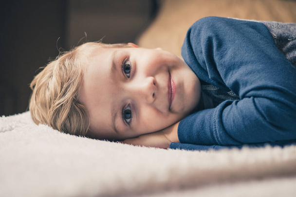 Smiling cute kid relaxing on the bed in the morning and looking at camera. - Foto, Bild