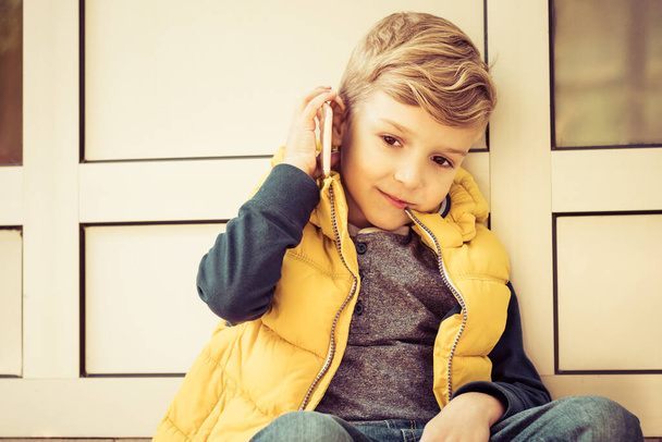 Cute kid talking on mobile phone while relaxing outdoors.  - Foto, immagini