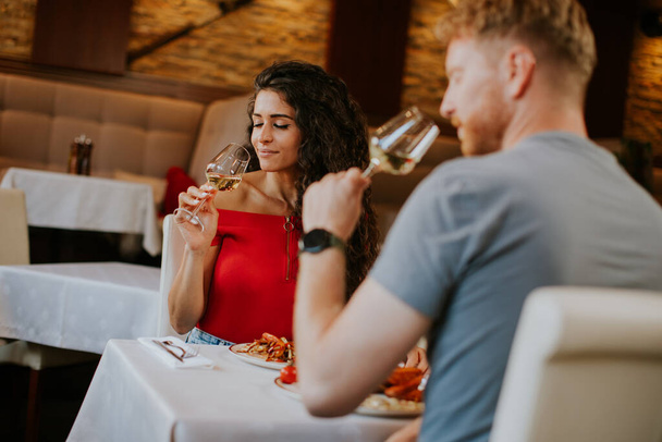 Handsome young couple having lunch with white wine in the restaurant - Photo, Image