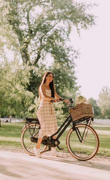 Mulher bonita com bicicleta elétrica e flores na cesta - Foto, Imagem