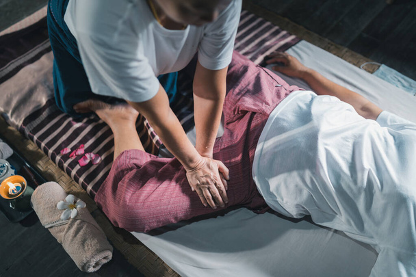 Massage and spa relaxing treatment of office syndrome traditional thai massage style. Asain senior female masseuse doing massage treat hand, back pain, arm pain, foot and stress for old woman tired. - Fotografie, Obrázek
