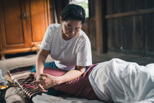 Массаж и спа расслабляющая процедура офисного синдрома традиционный тайский стиль массажа. Как старший массажист женщина делает массаж лечить боль в руке, спине, руке, ноге и стресс для старухи устал. - Фото, изображение