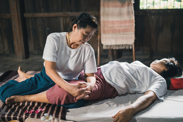 Massage and spa relaxing treatment of office syndrome traditional thai massage style. Asain senior female masseuse doing massage treat hand, back pain, arm pain, foot and stress for old woman tired. - Photo, image