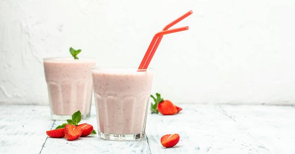Клубничный коктейль или молочный коктейль с ягодами и йогуртом в стеклянной банке на белом бетонном фоне. Вегетарианский здоровый напиток. место для текста, вид сверху, - Фото, изображение