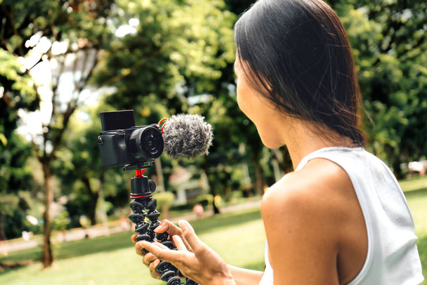 Young asian woman recording video with a camera for vlog and social media in a park. High quality photo - Photo, Image