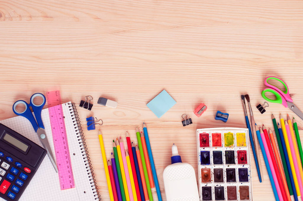 χρώματα, μολύβια, ψαλίδια, κόλλα και άλλα αξεσουάρ σε ξύλινο φόντο με χώρο για κείμενο, την έννοια της επιστροφής στο σχολείο. Υψηλής ποιότητας φωτογραφία - Φωτογραφία, εικόνα