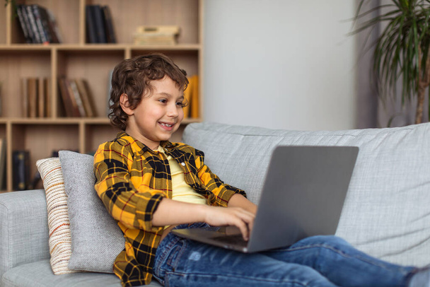 Cyber safety for kids. Young excited little boy typing on laptop, exploying internet at home, watching forbidden websites alone, free space - Fotoğraf, Görsel