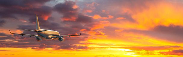 Αεροπλάνο. Τοπίο με μεγάλο επιβατικό αεροπλάνο πετάει στον δραματικό ουρανό στο πολύχρωμο ηλιοβασίλεμα. Ταξίδι. Τα επιβατικά αεροσκάφη προσγειώνονται το σούρουπο. Επαγγελματικό ταξίδι. Εμπορικό αεροπλάνο - Φωτογραφία, εικόνα