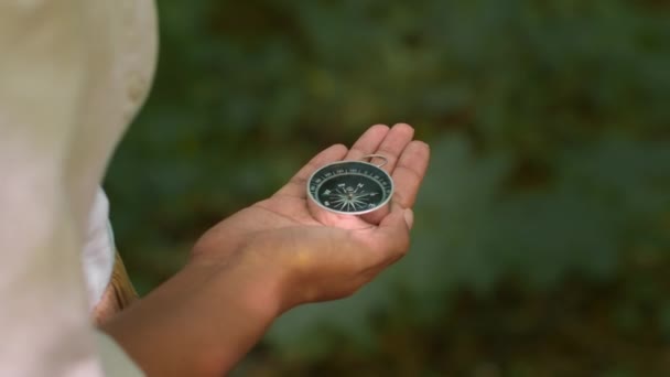 Woodland orienteering concept. Close up shot of compass in female hand, unrecognizable woman tourist looking for north at forest, slow motion, free space - Video, Çekim