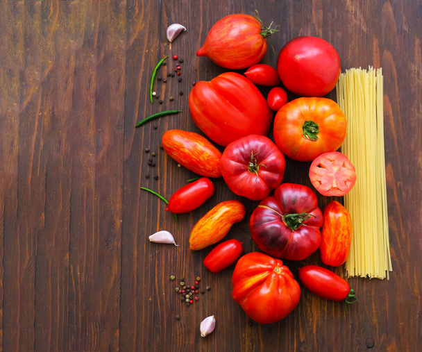 Fresh tomatoes and spaghetti on a wooden background. The concept of Italian cuisine or harvest festival. Close-up - Foto, Imagem