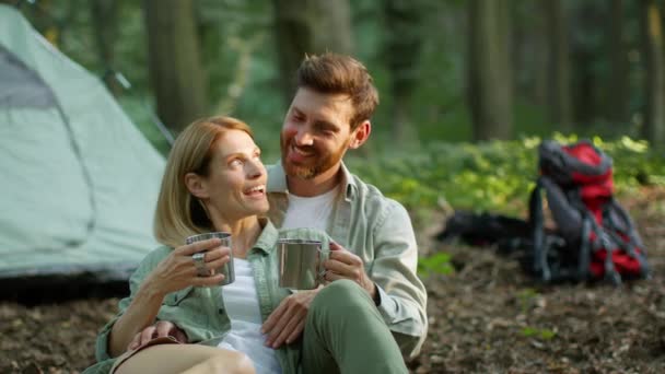 Happy rest. Close up portrait of positive middle aged couple in love drinking tea from metal cups, enjoying camping activity, laughing together, slow motion, free space - Metraje, vídeo