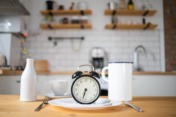 intermittent fasting concept alarm clock on kitchen table - Фото, зображення