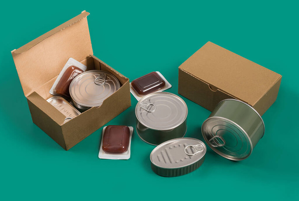 Canned food set, terrines cardboard boxes on green background. Horizontal photography made in studio. - Photo, Image