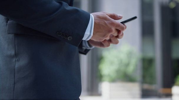 Businessman hands holding phone texting closeup. Man using smartphone walking. Unknown successful ceo going in black suit to business meeting sending messages on way. Downtown lifestyle concept. - Photo, Image