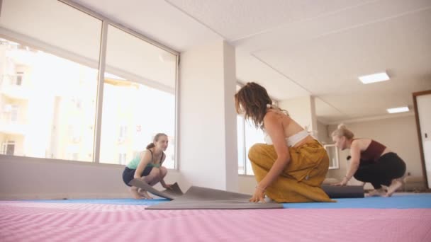 Three women puts down yoga mats and start the class. Mid shot - Imágenes, Vídeo