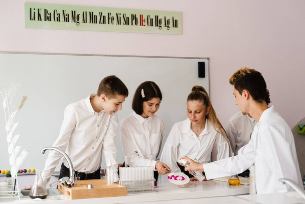 Education. Chemical experiments at a chemistry lesson at school. Children classmates making experiments in the laboratory - Zdjęcie, obraz