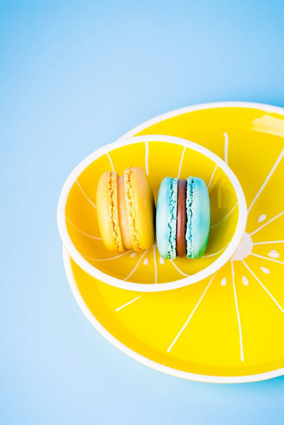 Blue and yellow macarons on a yellow plate - Valokuva, kuva