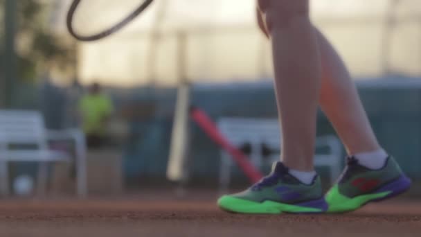 A woman hits a tennis ball from the court with a racket. Mid shot - Materiał filmowy, wideo
