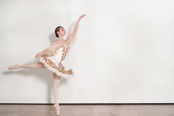 pretty ballerina performs ballet exercises in the studio against a white background - Φωτογραφία, εικόνα