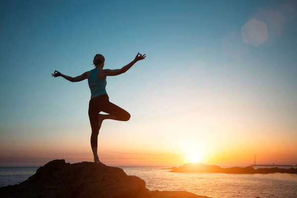 Silhouette woman yoga, meditation on the ocean beach seeing off the sun.    - Foto, immagini