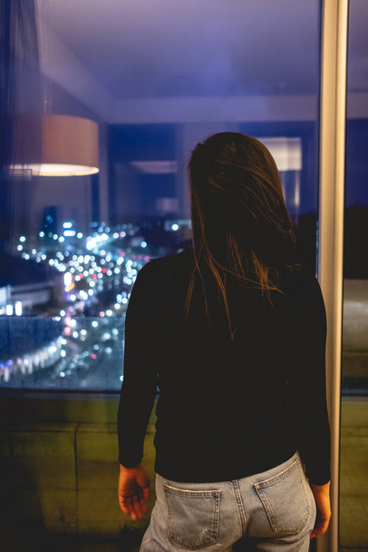 Сексуальная молодая бизнес-девушка перед большой витриной с разноцветными ночными городскими огнями - Фото, изображение