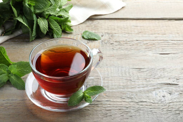 Cup of hot aromatic tea with mint on wooden table. Space for text - Foto, imagen