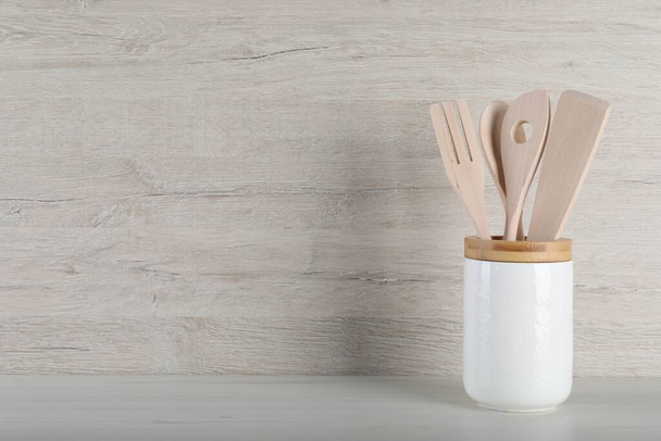 Holder with different kitchen utensils on white wooden table. Space for text - Foto, Imagen