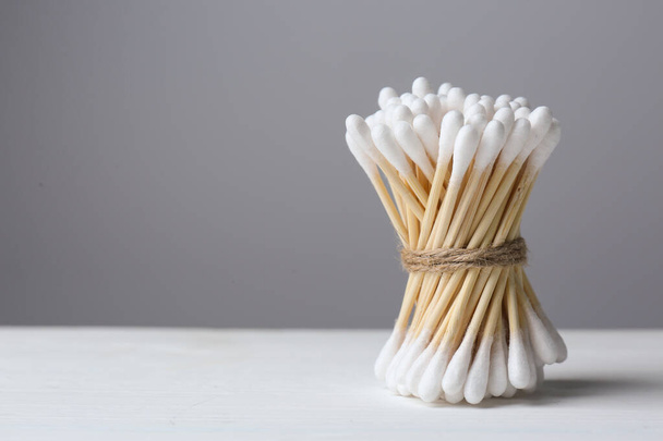 Many cotton buds on white wooden table against grey background, space for text - Photo, Image