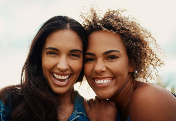 The right friendships bring nothing but happiness. Cropped portrait of two attractive young girlfriends smiling while standing together in a park - Foto, afbeelding