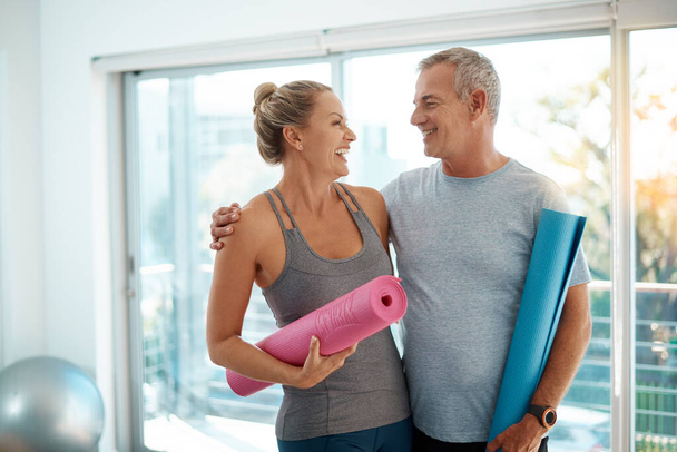 Мне нравится быть в форме с тобой. любящая зрелая пара, стоящая со своими ковриками для йоги дома - Фото, изображение