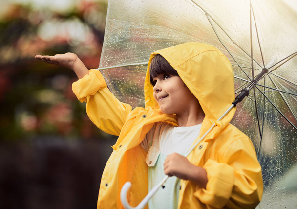 Rainy weather is my favourite type of weather. an adorable little boy in the rain outside - 写真・画像
