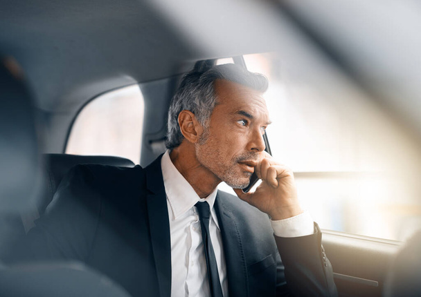 Ill pick you up on the way. a handsome mature businessman making a call from the backseat of a car during his morning commute - Foto, immagini