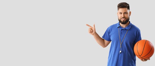 Portrait of male PE teacher pointing at something on light background with space for text - Foto, Imagem